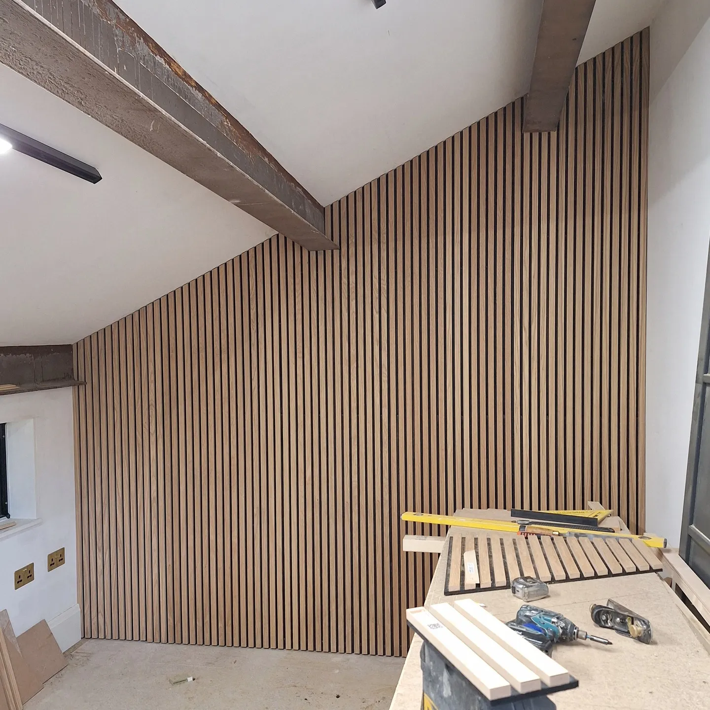 Acoustic timber slat wall being fitted to hide the utility cupboard