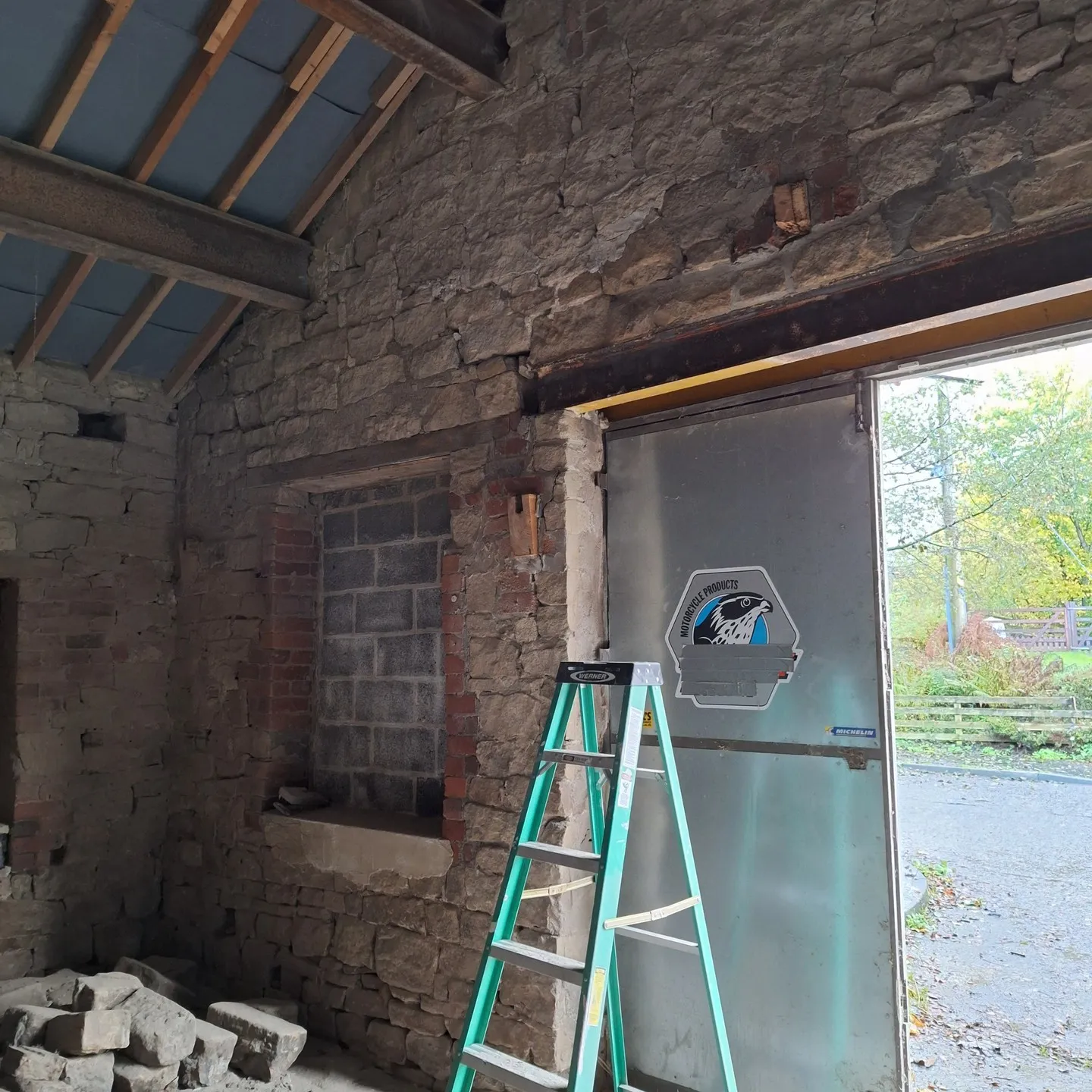Sandblasted stone walls inside the stable, showing patched openings and missing mortar